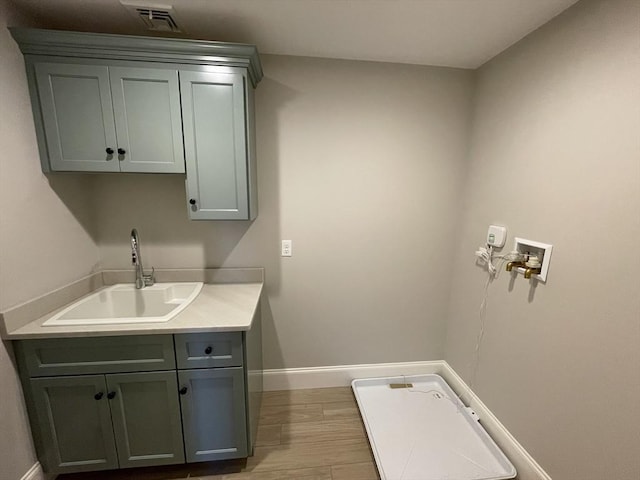 clothes washing area with hardwood / wood-style floors, cabinets, sink, and hookup for a washing machine