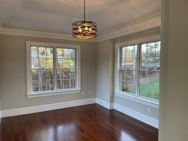 unfurnished dining area with ornamental molding, dark hardwood / wood-style flooring, a tray ceiling, and a notable chandelier