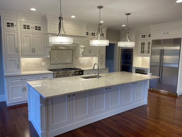 kitchen with sink, white cabinetry, stainless steel appliances, and a large island with sink