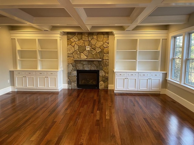 unfurnished living room featuring beamed ceiling, a stone fireplace, built in features, and dark wood-type flooring