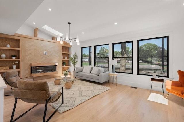 216 Aspinwall Ave, Brookline, MA 02446 - living room featuring light wood-style flooring, vaulted ceiling, recessed lighting, a skylight, and a high end fireplace