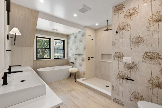 216 Aspinwall Ave, Brookline, MA 02446 - bathroom featuring wood finished floors, walk in shower, a freestanding tub, vanity, and recessed lighting