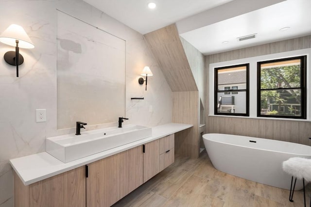 216 Aspinwall Ave, Brookline, MA 02446 - bathroom with vanity, a freestanding bath, wood finished floors, and tile walls