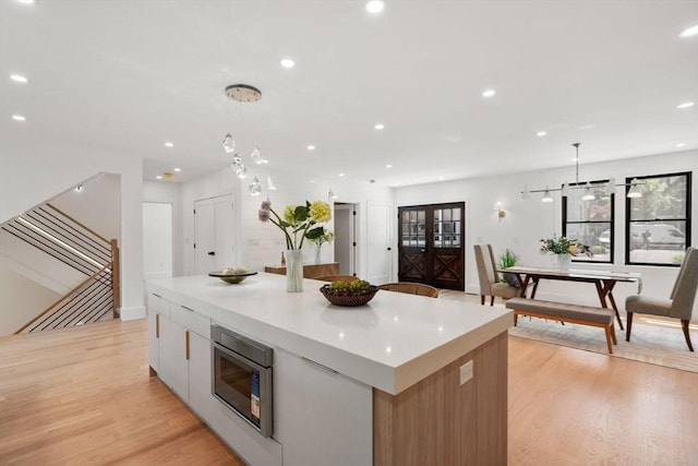 216 Aspinwall Ave, Brookline, MA 02446 - kitchen with stainless steel microwave, a large island, light wood-style flooring, hanging light fixtures, and recessed lighting