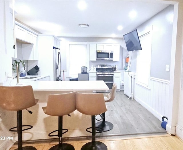 kitchen featuring a breakfast bar area, white cabinetry, sink, and stainless steel appliances