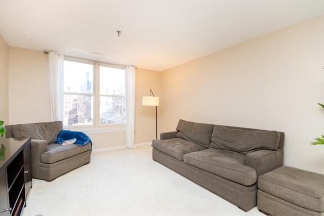 living area featuring baseboards and light colored carpet