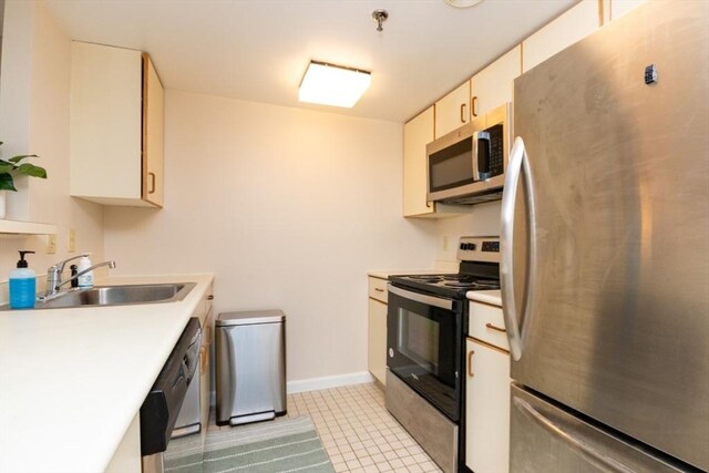 kitchen with light countertops, a sink, baseboards, and stainless steel appliances