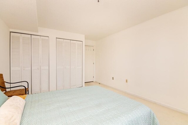 bedroom featuring baseboards, carpet, and two closets