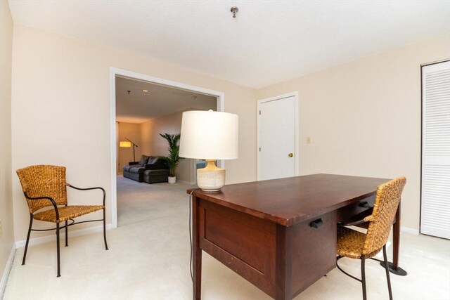 home office featuring baseboards and light carpet