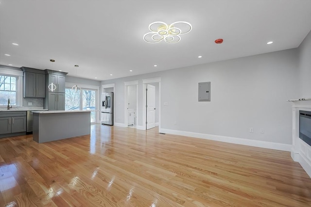 unfurnished living room with electric panel, light hardwood / wood-style floors, plenty of natural light, and sink