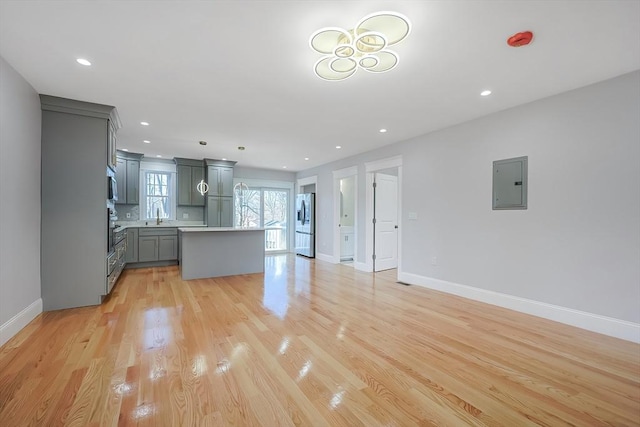 kitchen with electric panel, stainless steel fridge, light hardwood / wood-style floors, gray cabinets, and a kitchen island