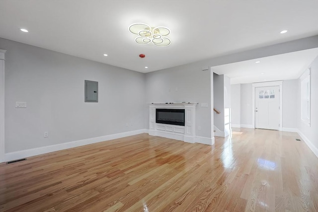 unfurnished living room featuring electric panel and light hardwood / wood-style flooring