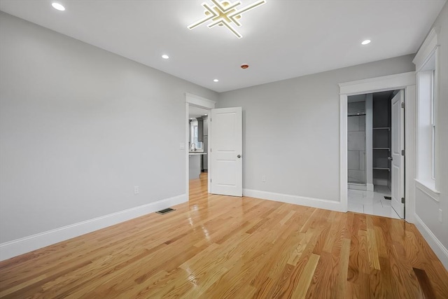 unfurnished bedroom featuring light wood-type flooring and a spacious closet