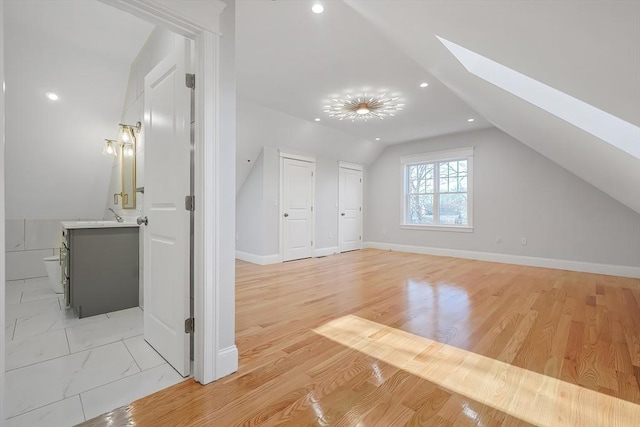 bonus room with vaulted ceiling with skylight and light hardwood / wood-style flooring