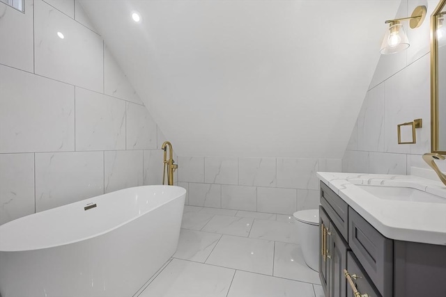 bathroom with vanity, lofted ceiling, a washtub, toilet, and tile walls