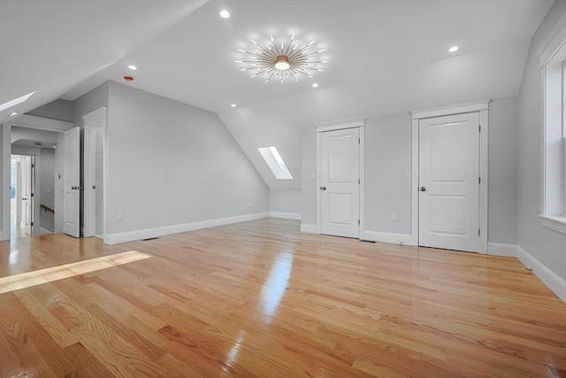 additional living space featuring light wood-type flooring and lofted ceiling with skylight