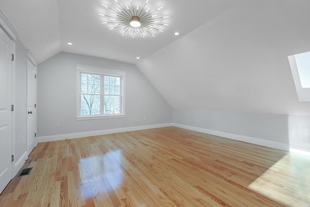 additional living space featuring light wood-type flooring and vaulted ceiling