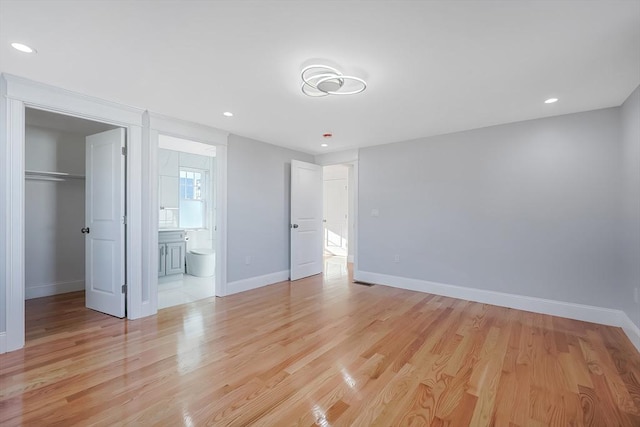 unfurnished bedroom with connected bathroom, a closet, and light hardwood / wood-style floors