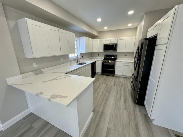 kitchen with white cabinetry, sink, kitchen peninsula, and appliances with stainless steel finishes