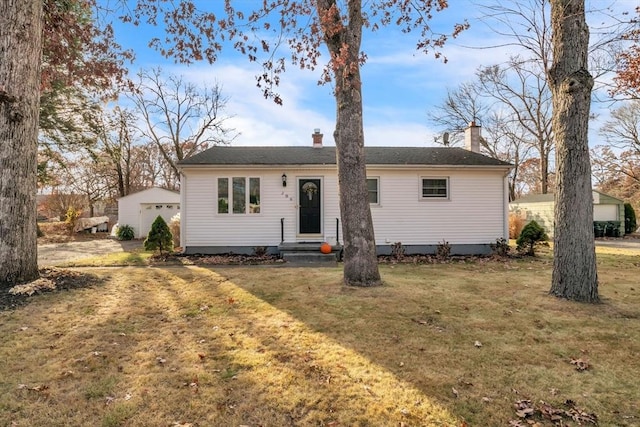 single story home featuring an outbuilding, a chimney, and a front yard