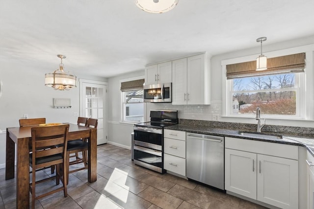 kitchen featuring appliances with stainless steel finishes, a wealth of natural light, a sink, and tasteful backsplash