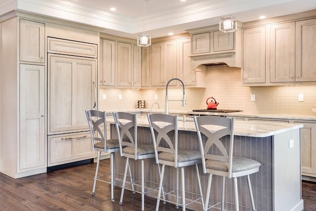 66 Simons Unit C, Mashpee, MA 02649 - kitchen with dark wood finished floors, ornamental molding, a breakfast bar, a center island with sink, and paneled built in fridge