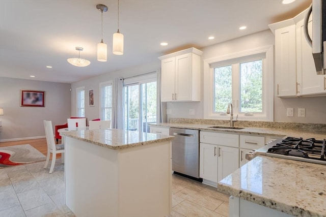 kitchen featuring a sink, light stone counters, stainless steel dishwasher, a center island, and recessed lighting