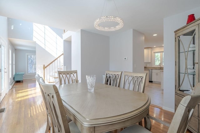 dining area with visible vents, baseboards, stairs, light wood-style floors, and baseboard heating