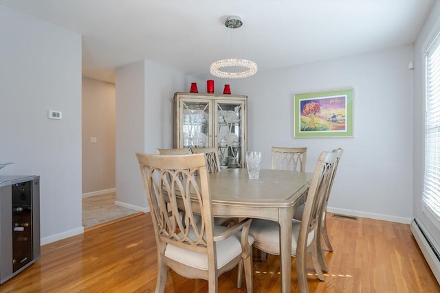 dining room with visible vents, a baseboard heating unit, baseboards, beverage cooler, and light wood-style floors