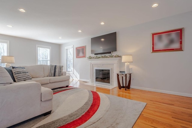 living room featuring recessed lighting, light wood-style flooring, baseboards, and a premium fireplace