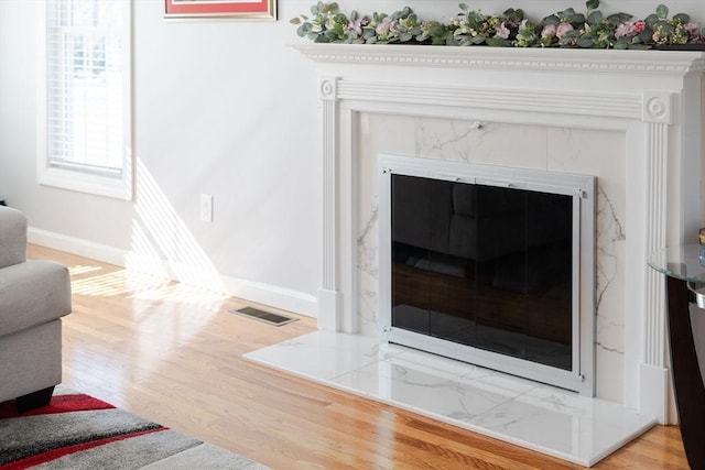 interior details featuring visible vents, wood finished floors, baseboards, and a premium fireplace