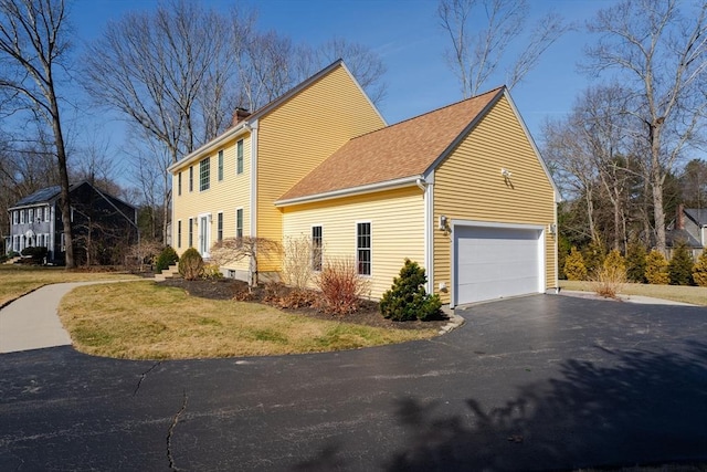 view of home's exterior with roof with shingles, a lawn, a chimney, driveway, and an attached garage