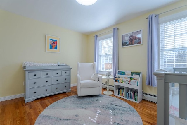 bedroom featuring a baseboard heating unit, baseboards, and wood finished floors