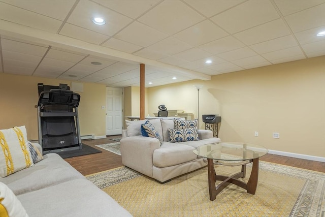 living room featuring a baseboard heating unit, a paneled ceiling, baseboards, and wood finished floors