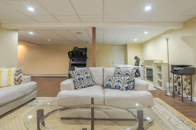 living area with recessed lighting, baseboards, a paneled ceiling, and wood finished floors