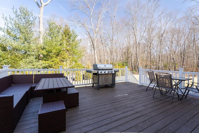 deck featuring outdoor dining space, a forest view, and grilling area