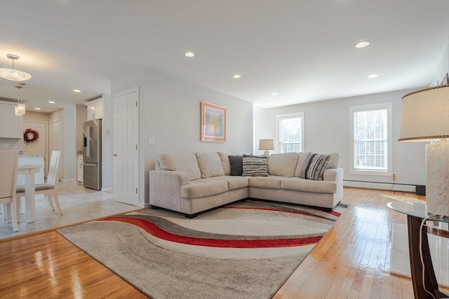 living room with light wood finished floors, recessed lighting, a baseboard heating unit, and baseboards