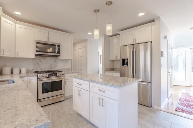 kitchen featuring a center island, pendant lighting, decorative backsplash, appliances with stainless steel finishes, and white cabinets