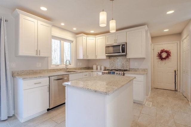 kitchen with a sink, stainless steel appliances, a kitchen island, and white cabinets