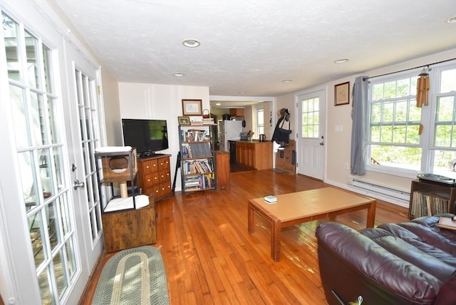 living area featuring baseboard heating, hardwood / wood-style floors, recessed lighting, and a textured ceiling