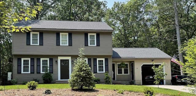 colonial inspired home with a garage, concrete driveway, roof with shingles, and a front lawn