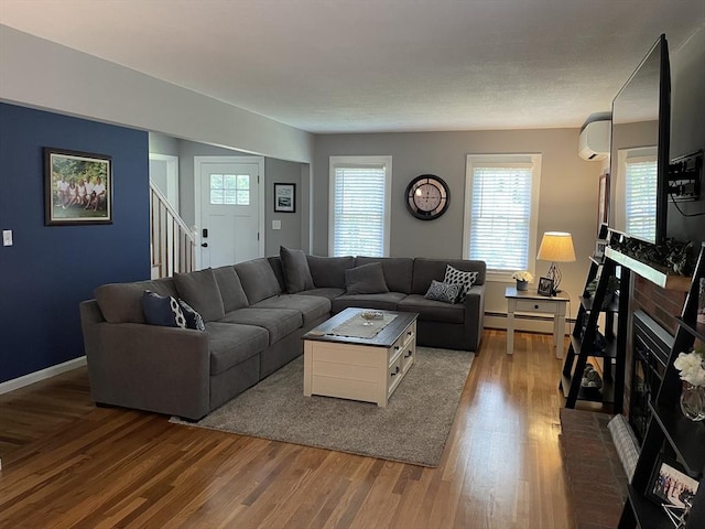 living room with a baseboard radiator, stairs, baseboards, and wood finished floors