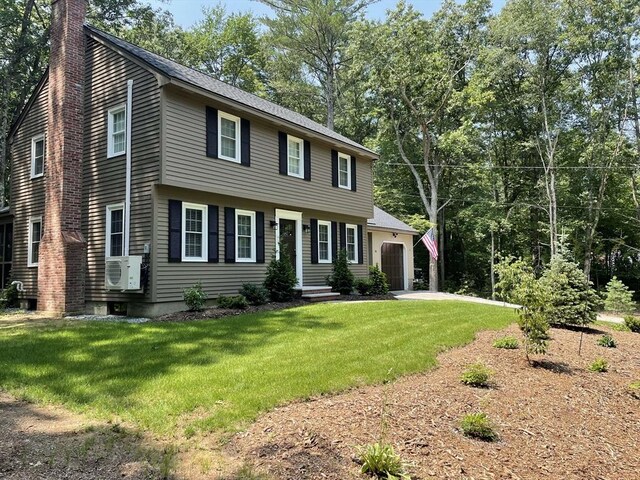 colonial-style house with ac unit, a chimney, and a front lawn