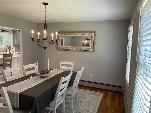 dining space with a baseboard heating unit, dark wood finished floors, and an inviting chandelier