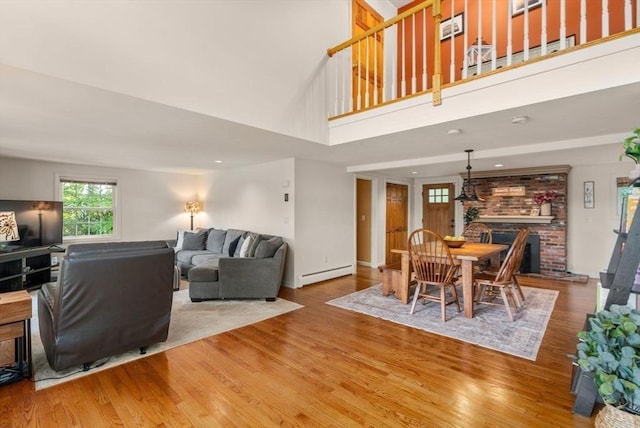 72 S Shore Dr, Sturbridge, MA 01566 - dining room with a baseboard heating unit, a brick fireplace, wood finished floors, a high ceiling, and baseboards