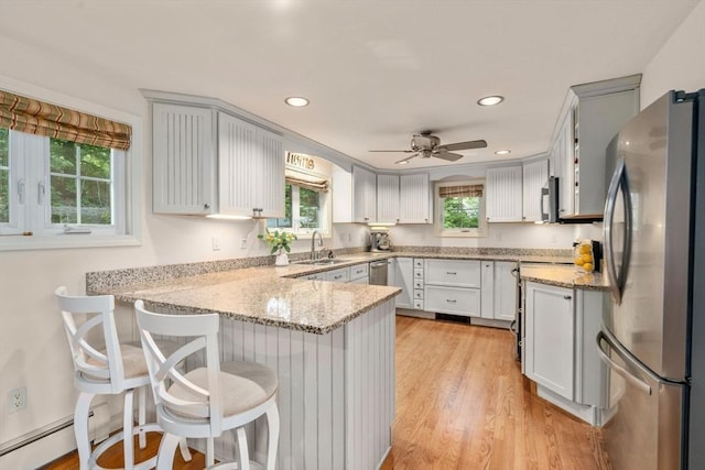 72 S Shore Dr, Sturbridge, MA 01566 - kitchen with appliances with stainless steel finishes, a peninsula, light wood-style floors, a sink, and light stone counters