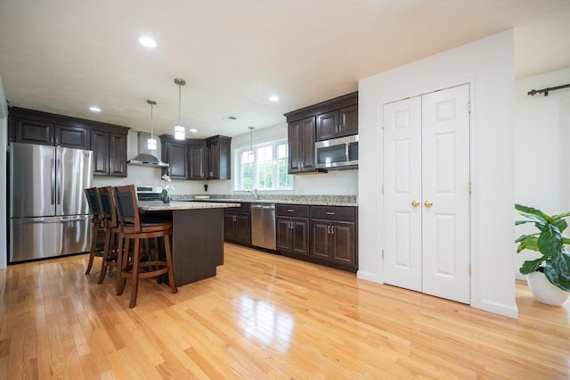 7 Willow Brook Ln, Blackstone, MA 01504 - kitchen featuring stainless steel appliances, wall chimney range hood, dark brown cabinets, light wood-style floors, and a kitchen breakfast bar