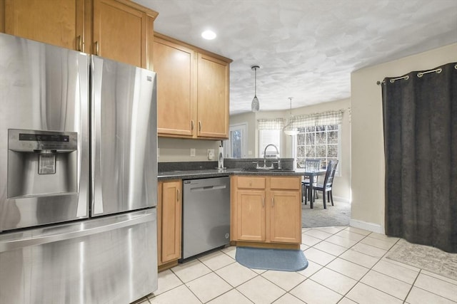 kitchen with appliances with stainless steel finishes, decorative light fixtures, sink, dark stone counters, and light tile patterned floors