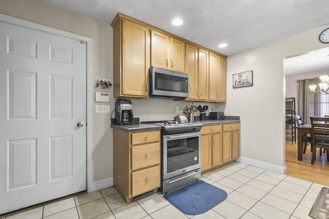 kitchen with an inviting chandelier, stainless steel appliances, and light tile patterned floors