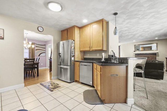 kitchen with appliances with stainless steel finishes, decorative light fixtures, sink, a kitchen breakfast bar, and kitchen peninsula